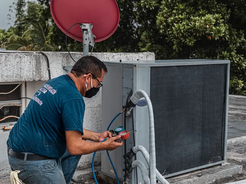 Technician checking an air conditioning unit with gauges