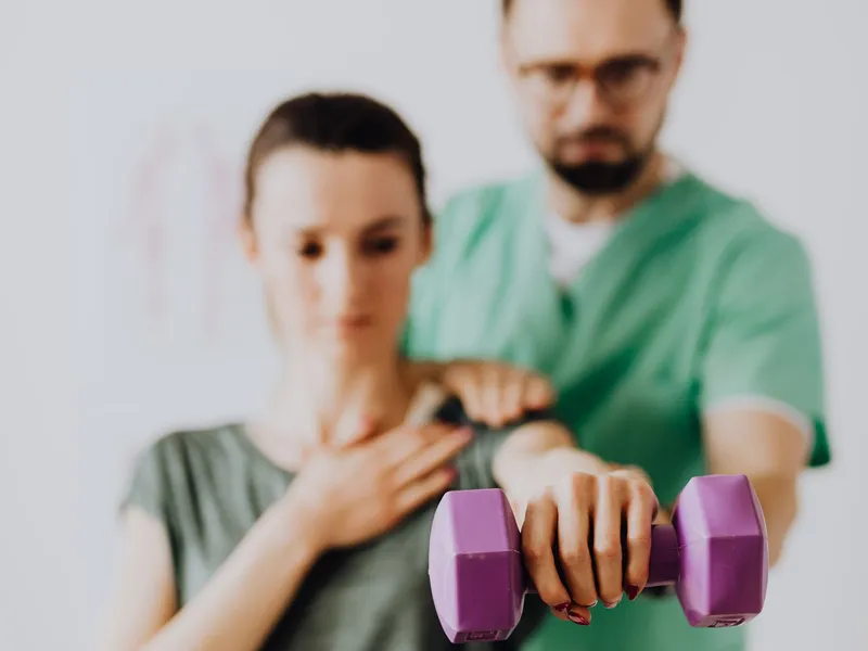 Physical therapist guiding a patient through a dumbbell exercise