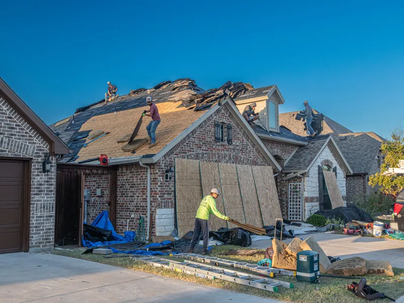 Crew tearing off an old roof on a suburban house